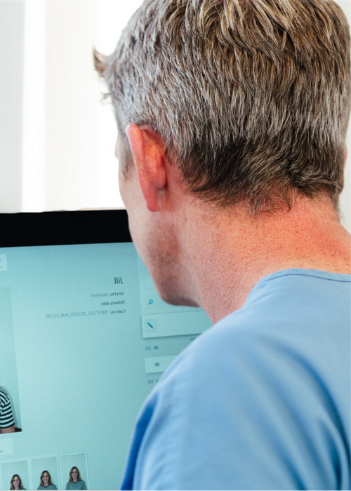 Dr Robin Hanna sitting in front of computer, looking a photos and planning clinical treatment