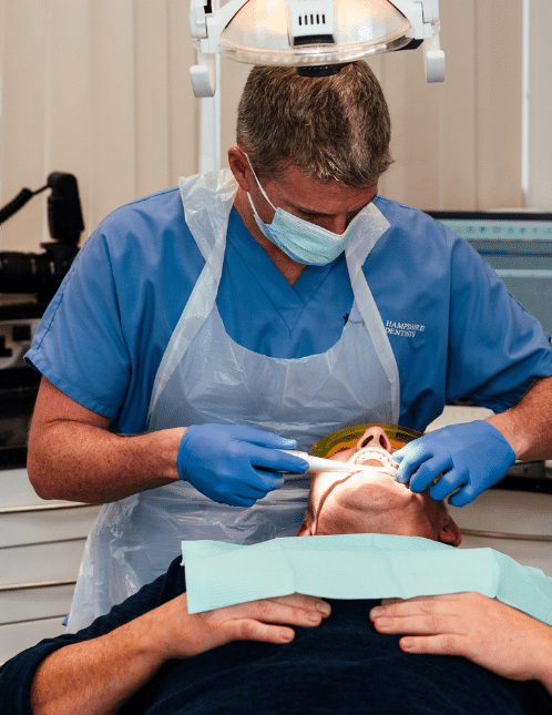 Dental Implants - Hampshire Dentists Pain Free Dentist in Southampton Dr Robin Hanna adjusting implant bridge for patient in dental chair