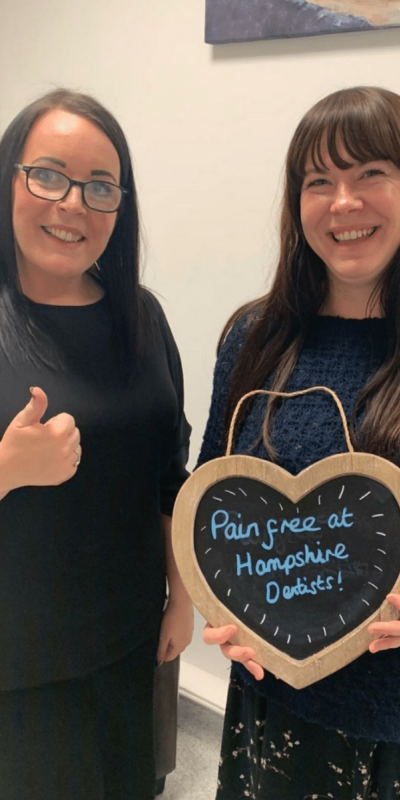 Patient Photos - Hampshire Dentists Pain Free Dentist in Southampton Patient with Practice manager at Hampshire Dentists, holding a sign saying "Pain free at Hampshire Dentists" emphasising pain-free dental care.