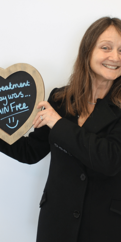 Patient Photos - Hampshire Dentists Pain Free Dentist in Southampton Patient at Hampshire Dentists, holding a sign saying " My treatment today was pain free " emphasising pain-free dental care.