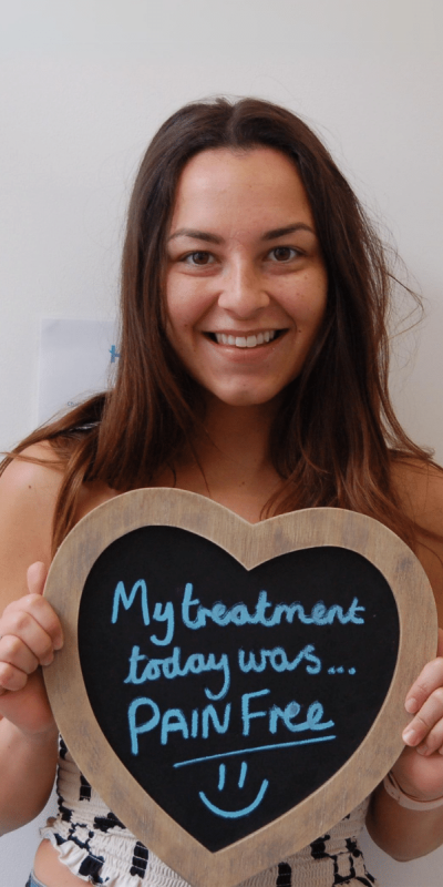 Patient Photos - Hampshire Dentists Pain Free Dentist in Southampton Patient at Hampshire Dentists, holding a sign saying " My treatment today was pain free " emphasising pain-free dental care.