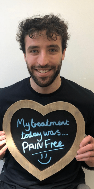 Patient Photos - Hampshire Dentists Pain Free Dentist in Southampton Patient at Hampshire Dentists, holding a sign saying " My treatment today was pain free " emphasising pain-free dental care.