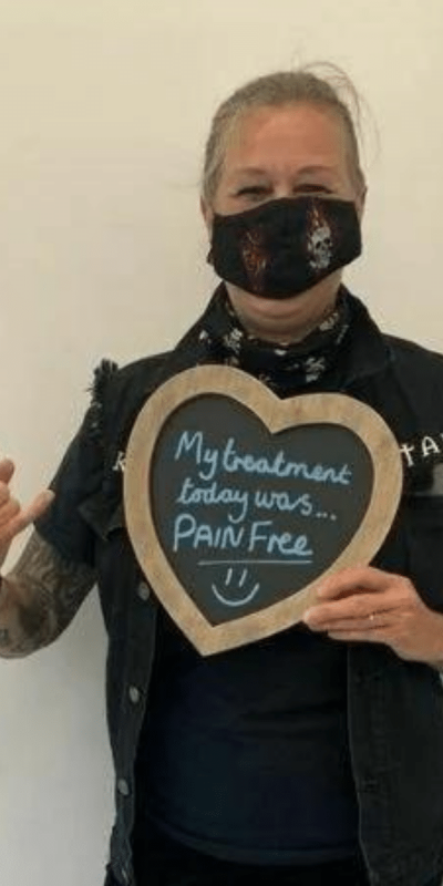 Patient Photos - Hampshire Dentists Pain Free Dentist in Southampton Patient at Hampshire Dentists, holding a sign saying " My treatment today was pain free " emphasising pain-free dental care.