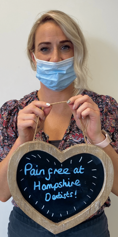 Patient Photos - Hampshire Dentists Pain Free Dentist in Southampton Patient at Hampshire Dentists, holding a sign saying "Pain free at Hampshire Dentists" emphasising pain-free dental care.