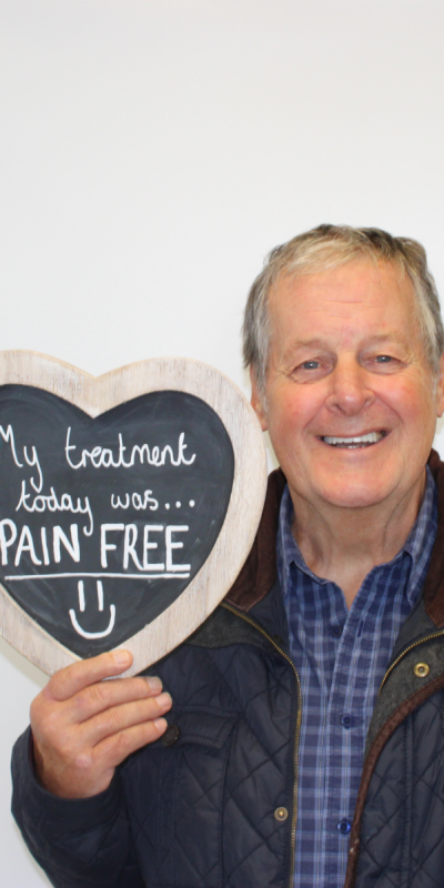 Patient at Hampshire Dentists, holding a sign saying " My treatment today was pain free " emphasising pain-free dental care.