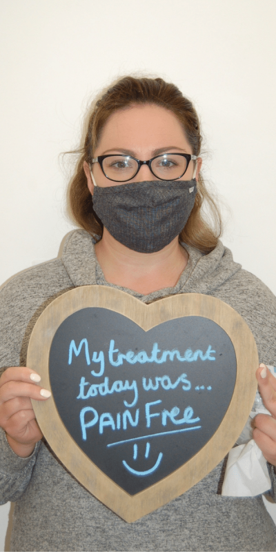 Patient Photos - Hampshire Dentists Pain Free Dentist in Southampton Patient at Hampshire Dentists, holding a sign saying " My treatment today was pain free " emphasising pain-free dental care.