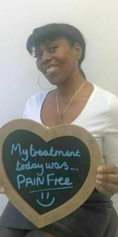 Patient at Hampshire Dentists, holding a sign saying " My treatment today was pain free " emphasising pain-free dental care.