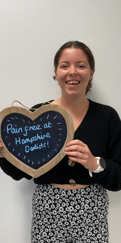Patient Photos - Hampshire Dentists Pain Free Dentist in Southampton Patient at Hampshire Dentists, holding a sign saying "Pain free at Hampshire Dentists" emphasising pain-free dental care.