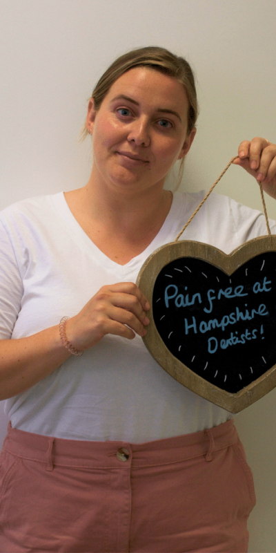 Patient Photos - Hampshire Dentists Pain Free Dentist in Southampton Patient at Hampshire Dentists, holding a sign saying "Pain free at Hampshire Dentists" emphasising pain-free dental care.