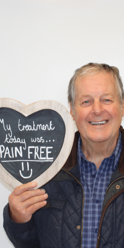 Patient Photos - Hampshire Dentists Pain Free Dentist in Southampton Patient at Hampshire Dentists, holding a sign saying " My treatment today was pain free " emphasising pain-free dental care.