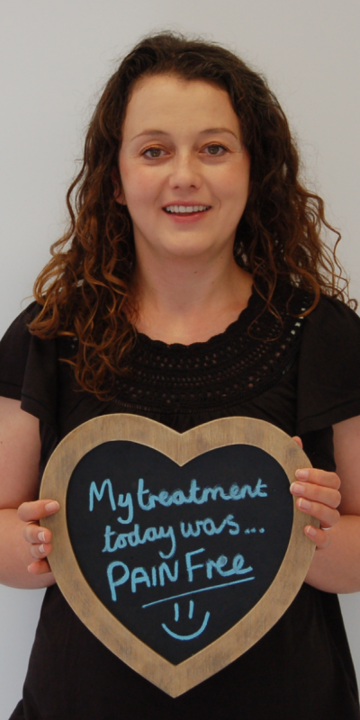 Patient at Hampshire Dentists, holding a sign saying " My treatment today was pain free " emphasising pain-free dental care.