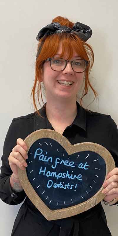Patient Photos - Hampshire Dentists Pain Free Dentist in Southampton Patient at Hampshire Dentists, holding a sign saying "Pain free at Hampshire Dentists" emphasising pain-free dental care.