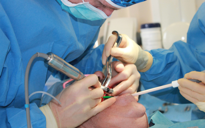 Referrals - Hampshire Dentists Pain Free Dentist in Southampton Dr Robin Hanna, supported by dental nurse, mid way through placing dental implant, sowing surgical procedure