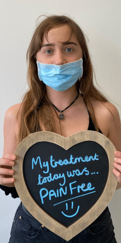 Patient Photos - Hampshire Dentists Pain Free Dentist in Southampton Patient at Hampshire Dentists, holding a sign saying " My treatment today was pain free " emphasising pain-free dental care.
