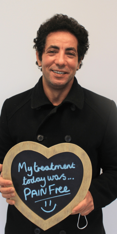 Patient Photos - Hampshire Dentists Pain Free Dentist in Southampton Patient at Hampshire Dentists, holding a sign saying " My treatment today was pain free " emphasising pain-free dental care.