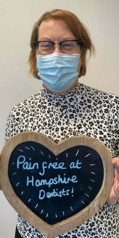 Patient Photos - Hampshire Dentists Pain Free Dentist in Southampton Patient at Hampshire Dentists, holding a sign saying "Pain free at Hampshire Dentists" emphasising pain-free dental care.