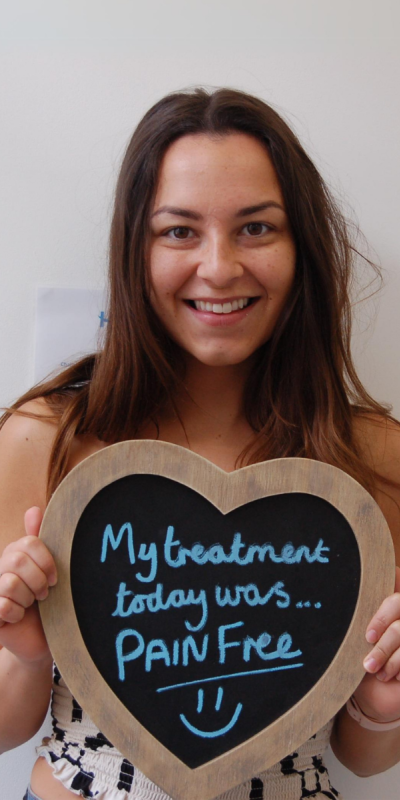 Patient at Hampshire Dentists, holding a sign saying " My treatment today was pain free " emphasising pain-free dental care.