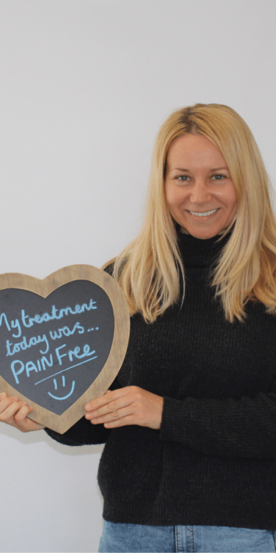 Patient Photos - Hampshire Dentists Pain Free Dentist in Southampton Patient at Hampshire Dentists, holding a sign saying " My treatment today was pain free " emphasising pain-free dental care.