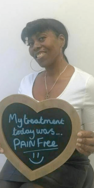 Patient Photos - Hampshire Dentists Pain Free Dentist in Southampton Patient at Hampshire Dentists, holding a sign saying " My treatment today was pain free " emphasising pain-free dental care.