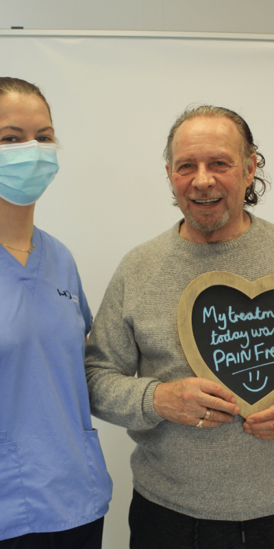 Patient Photos - Hampshire Dentists Pain Free Dentist in Southampton Patient with Dental nurse at Hampshire Dentists, holding a sign saying "My treatment today was pain free" emphasising pain-free dental care