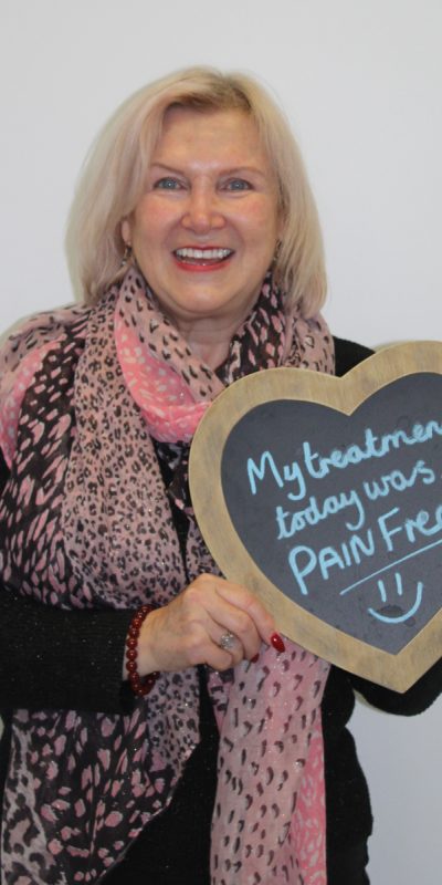 Patient at Hampshire Dentists, holding a sign saying " My treatment today was pain free " emphasising pain-free dental care.