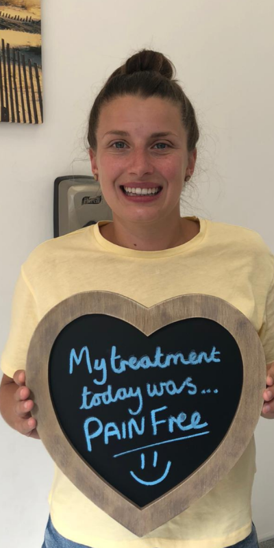 Patient at Hampshire Dentists, holding a sign saying " My treatment today was pain free " emphasising pain-free dental care.
