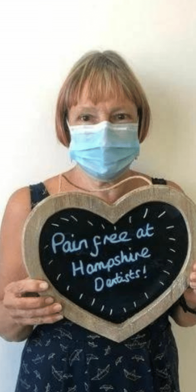 Patient Photos - Hampshire Dentists Pain Free Dentist in Southampton Patient at Hampshire Dentists, holding a sign saying "Pain free at Hampshire Dentists" emphasising pain-free dental care.