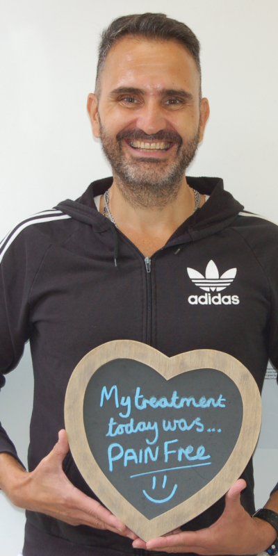 Patient at Hampshire Dentists, holding a sign saying " My treatment today was pain free " emphasising pain-free dental care.