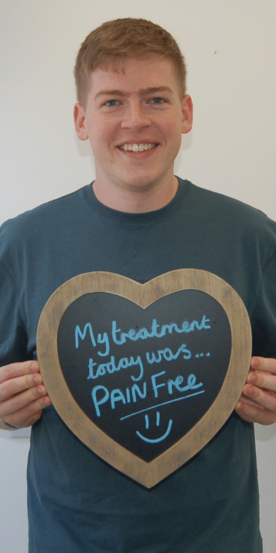 Patient Photos - Hampshire Dentists Pain Free Dentist in Southampton Patient at Hampshire Dentists, holding a sign saying " My treatment today was pain free " emphasising pain-free dental care.