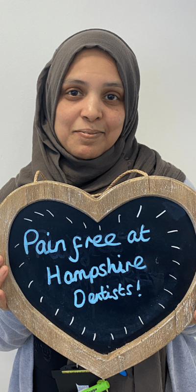 Patient Photos - Hampshire Dentists Pain Free Dentist in Southampton Patient at Hampshire Dentists, holding a sign saying "Pain free at Hampshire Dentists" emphasising pain-free dental care.