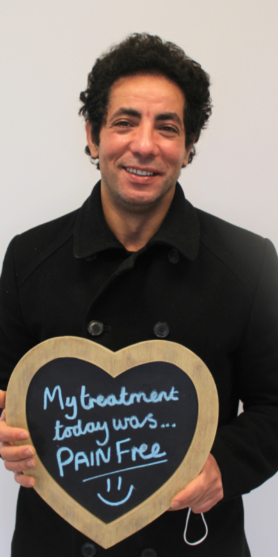 Patient at Hampshire Dentists, holding a sign saying " My treatment today was pain free " emphasising pain-free dental care.