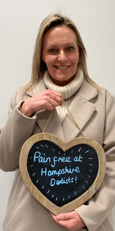 Patient Photos - Hampshire Dentists Pain Free Dentist in Southampton Patient at Hampshire Dentists, holding a sign saying "Pain free at Hampshire Dentists" emphasising pain-free dental care.
