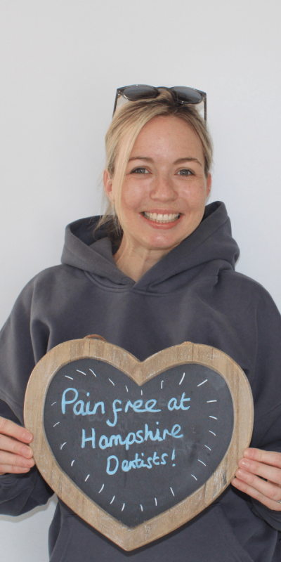 Patient Photos - Hampshire Dentists Pain Free Dentist in Southampton Patient at Hampshire Dentists, holding a sign saying "Pain free at Hampshire Dentists" emphasising pain-free dental care.