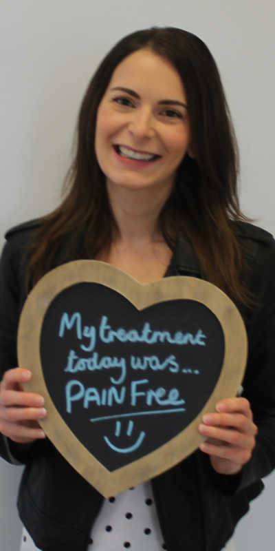 Patient at Hampshire Dentists, holding a sign saying " My treatment today was pain free " emphasising pain-free dental care.