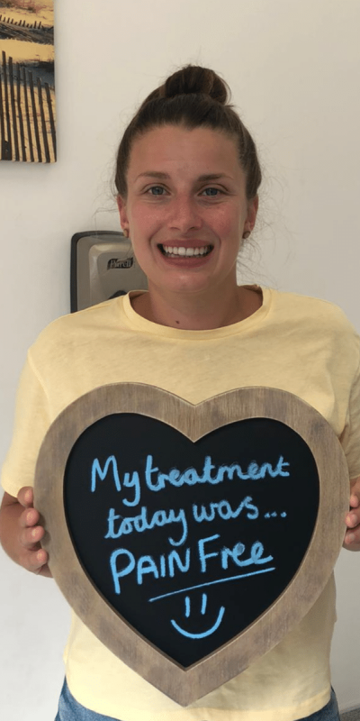 Patient Photos - Hampshire Dentists Pain Free Dentist in Southampton Patient at Hampshire Dentists, holding a sign saying " My treatment today was pain free " emphasising pain-free dental care.