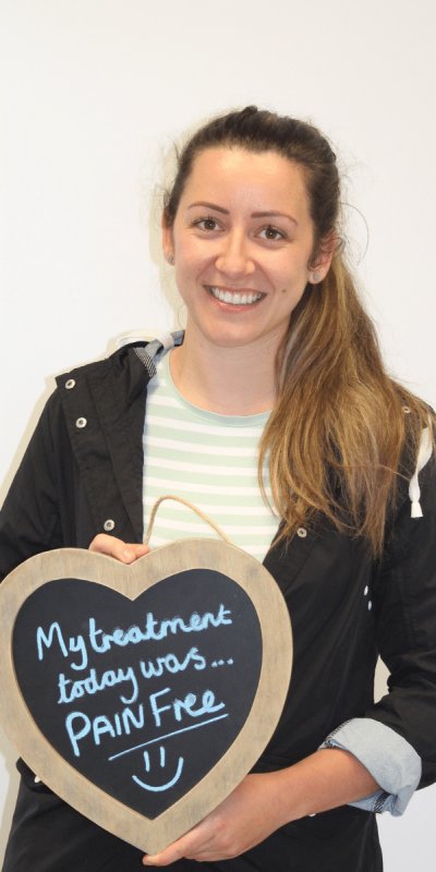 Patient Photos - Hampshire Dentists Pain Free Dentist in Southampton Patient at Hampshire Dentists, holding a sign saying " My treatment today was pain free " emphasising pain-free dental care.