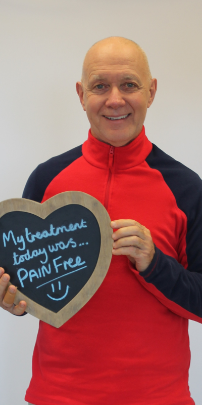 Patient at Hampshire Dentists, holding a sign saying " My treatment today was pain free " emphasising pain-free dental care.